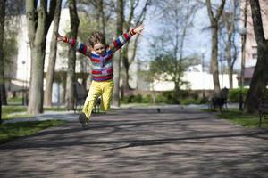 gelukkig kind is jumping omhoog voor een wandelen in de park. foto