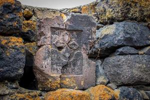 dichtbij omhoog steen kruis Aan ruw steen muur concept foto. historisch graven en hoofd stenen. rotsen vol van de mos structuur in natuur voor behang. foto