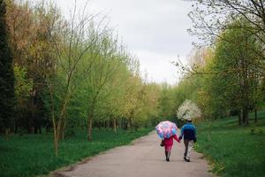 senior paar wandelen in het voorjaar park. oude man en vrouw met paraplu op een regenachtige dag buiten. kopieer ruimte. selectieve aandacht.