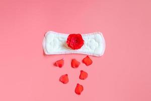 maandverband en rode bloem op roze achtergrond. menstruatie concept. foto