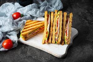 club belegd broodje met ham, tomaat, groen en kaas. gegrild panini foto