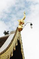 gouden naga en klokken hangende Aan kunst dak van boeddhistisch tempel met blauw lucht in Thailand foto