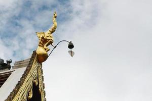 gouden naga en klokken hangende Aan kunst dak van boeddhistisch tempel met blauw lucht in Thailand foto