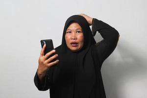 midden- oud Aziatisch Dames vervelend hijab voelt verdrietig lezing slecht nieuws Aan mobiel telefoon foto