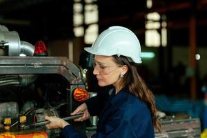 een gelukkig jong vrouw arbeider van een groot machinerie onderhoud fabriek in een blauw jurk en een wit beschermend hoed. onderhoud onderhoud. fabriek veiligheid. banier beeld foto