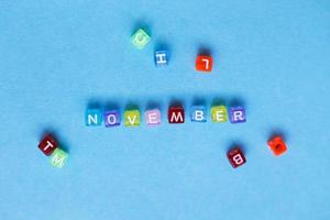 opschrift november gemaakt door veelkleurig plastic kubussen Aan een blauw achtergrond. foto