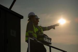 een team van elektrisch ingenieurs inspecteren zonne- panelen in een honderd acre veld, in de avond na voltooien de dagelijks werk taken met de instelling zon. foto