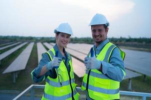 een team van elektrisch ingenieurs inspecteren zonne- panelen in een honderd hectare van gras Aan de op het dak van energie opslagruimte station, in de avond na voltooien de dagelijks werk taken met de instelling zon foto