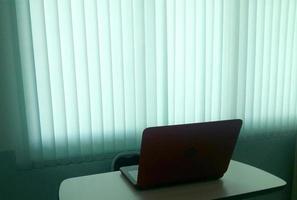 notebook op tafel met blind lichtgordijn foto