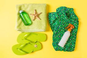 vlak leggen samenstelling met groen strand accessoires Aan geel kleur achtergrond. zomer vakantie achtergrond. vakantie en reizen items top visie foto