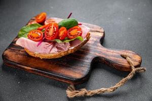 bruschetta tomaat belegd broodje ham, sla tussendoortje maaltijd voedsel tussendoortje Aan de tafel kopiëren ruimte voedsel achtergrond rustiek top visie foto