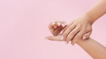 vrouw toont haar manicure op roze achtergrond met kopie ruimte