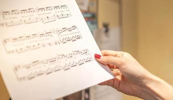 vrouw hand- van musicus of componist hand- schrijft een lied of een musical werk, schrijven aantekeningen met potlood Aan de pentagram. foto