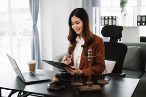 Aziatisch advocaat vrouw werken met een laptop en tablet in wet kantoor. wettelijk en wettelijk onderhoud concept. op zoek Bij camera foto