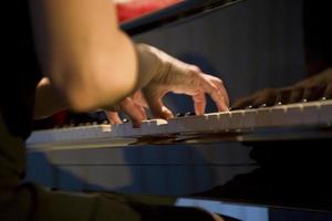 detailopname Aan de handen van een vrouw spelen de piano met muziek- sleutels foto