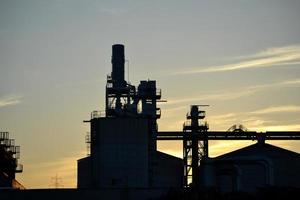 metaal pijpen en silo's in fabriek, zonsondergang lucht foto