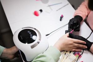 top visie van manicure meester werken met vrouw cliënt in schoonheid salon. manicure maakt vrouw nagel. foto