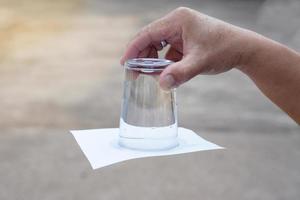 detailopname hand- houden en beurt een glas van water over- omlaag. gedekt de glas met papier. concept, wetenschap experiment over lucht en vloeistof druk. gemakkelijk wetenschap onderwerpen werkzaamheid, onderwijs. foto
