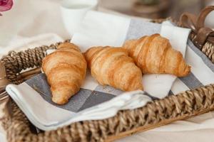 vers croissants in een rieten mand Aan de tafel De volgende naar een vaas van lila tulpen. foto