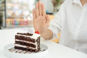 schoonheid slank vrouw lichaam verwarren chocola taart. vrouw in restaurant behaalt gewicht verlies doel voor gezond leven, gek over dunheid, dun taille, voedingsdeskundige. eetpatroon, lichaam vorm geven aan. foto