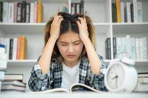 Aziatisch leerling vrouw hebben ongerustheid omdat van examens, vrouw bereiden voor test en aan het leren lessen in de bibliotheek. spanning, wanhoop, haast, misverstand lezing, ontmoedigd, verwachting, kennis foto