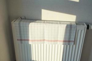 geel kleur handdoek drogen Aan verwarming radiator, foto