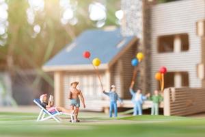 miniatuurmensen, gelukkige familie die in het gazon van de achtertuin spelen. leven thuis concept