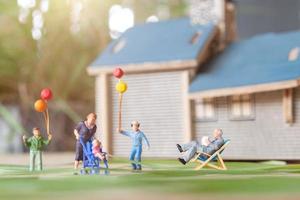 miniatuurmensen, gelukkige familie die in het gazon van de achtertuin spelen. leven thuis concept foto
