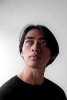 dramatisch laag licht portret van knap Aziatisch Mens op zoek omhoog. kant licht effect foto