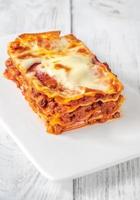 portie lasagne op wit bord foto