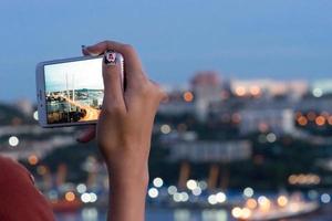 meisje hand met een smartphone die foto's maakt van de gouden brug. vladivostok, rusland foto