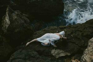 mooi bruid aan het liegen Aan rotsachtig kust met scheuren Aan rotsachtig oppervlakte landschap foto