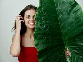 glimlachen vrouw met groen palm blad in rood zwempak detailopname foto