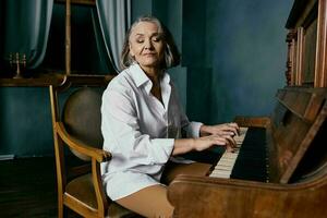 ouderen vrouw zittend Aan een stoel in de buurt de piano muziek- prestatie foto