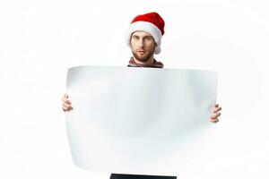 knap Mens in een Kerstmis hoed met wit mockup poster Kerstmis licht achtergrond foto