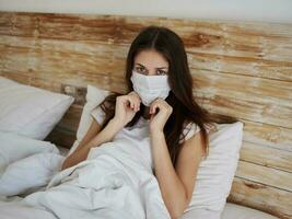 jong vrouw in een medisch masker leugens in bed top visie foto