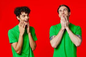 vrolijk vrienden in groen t-shirts houden Aan naar de gezicht van emotie foto