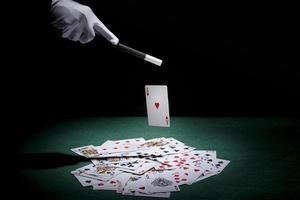 goochelaar truc speelkaarten uitvoeren met toverstaf pokertafel foto