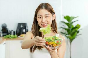 eetpatroon, dieet Aziatisch jong vrouw of meisje gebruik vork Bij sla Aan mengen groenten, groen salade schaal, eten voedsel is laag dik mooi zo Gezondheid. voedingsdeskundige vrouw, gewicht verlies voor gezond persoon. foto