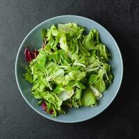 groen salade bladeren in kom Aan zwart tafel. foto