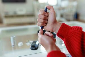 vrouw gebruik makend van lancet Aan vinger. vrouw aan het doen bloed suiker test Bij huis in een leven kamer. foto