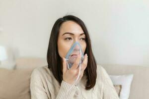 ziek Aziatisch vrouw maken inademing, geneeskunde is de het beste geneesmiddel. ziek vrouw vervelend een zuurstof masker en ondergaan behandeling voor covid19. vrouw met een inhalator foto