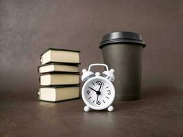 horloge, boeken, een kop van koffie. de concept van bedrijf, opleiding, en opleiding. lezing boeken en voorbereidingen treffen voor examens foto