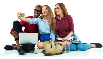 gelukkig studenten met boeken, laptop, Tassen en maakt selfie Aan wit achtergrond foto