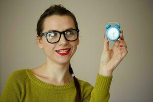 weinig blauw alarm klok in de handen van een emotioneel jong vrouw foto