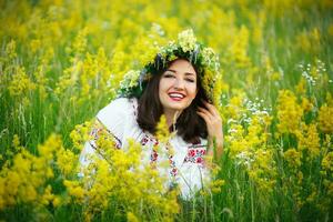 jong glimlachen meisje in oekraïens kostuum met een krans Aan zijn hoofd in een weide foto