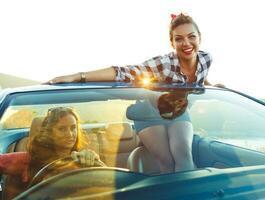 twee jong meisjes het rijden een cabriolet foto