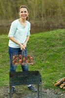 jong meisje voorbereidingen treffen voedsel Aan rooster foto