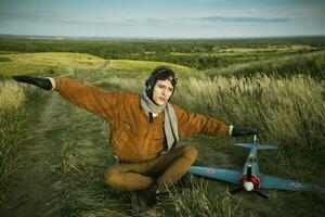 vent in wijnoogst kleren piloot met een vliegtuig model- buitenshuis foto