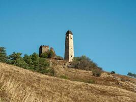 zonnig middag in de Kaukasus bergen. middag in de Kaukasus bergen. middeleeuws toren Aan herfst berg helling achtergrond. Ingoesjetië regio. foto